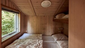 A wooden cabin room with two beds, a window, and a ceiling light. - 6 Person Holiday Park Home in Bryrup (Bryrup)