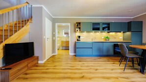 A modern kitchen with wooden flooring, a built-in TV, and a dining area with a table and chairs.