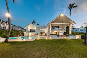 A modern two-story house with a swimming pool, large windows, and a well-maintained lawn.