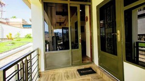 A hotel entrance with a wooden floor, a welcome mat, and a glass door. - Homescapes (Kigali)