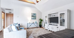 Una sala de estar con un sofá, televisor y armarios.