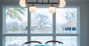 A room with a large window, a ceiling light fixture, and a view of the outside.