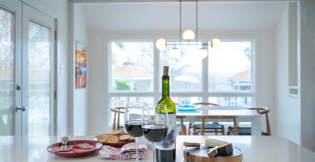 A dining table with a bottle of wine, glasses, and a plate of food.