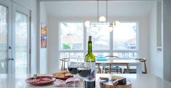 Una mesa de comedor con una botella de vino, copas y un plato de comida.