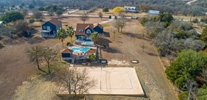 Vista aérea de una zona residencial con varias casas, un campo abierto y una piscina.