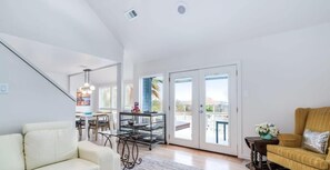 A spacious living room with a sofa, a dining table, and a balcony with glass doors.