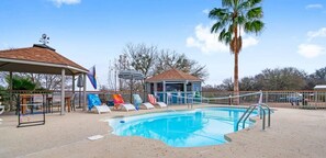Una piscina con sillas de descanso, un pabellón y una palmera.