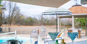 A poolside area with a covered seating area, a pool, and a gazebo in the background.