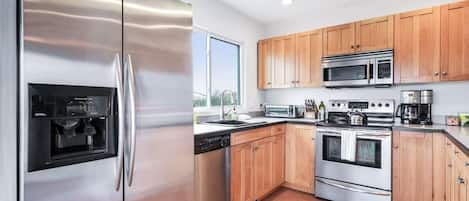 Una cocina moderna con electrodomésticos de acero inoxidable, armarios de madera y un ventanal que proporciona luz natural.