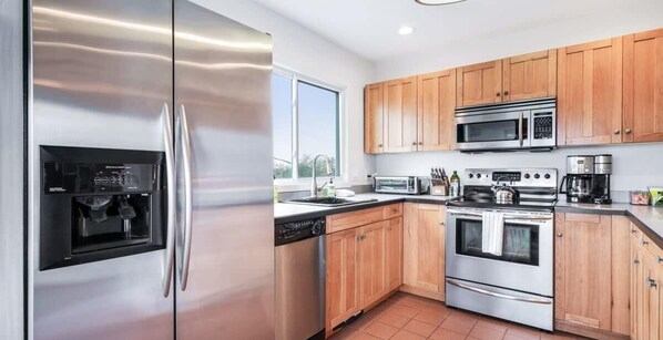 Una cocina moderna con electrodomésticos de acero inoxidable, armarios de madera y un ventanal que proporciona luz natural.