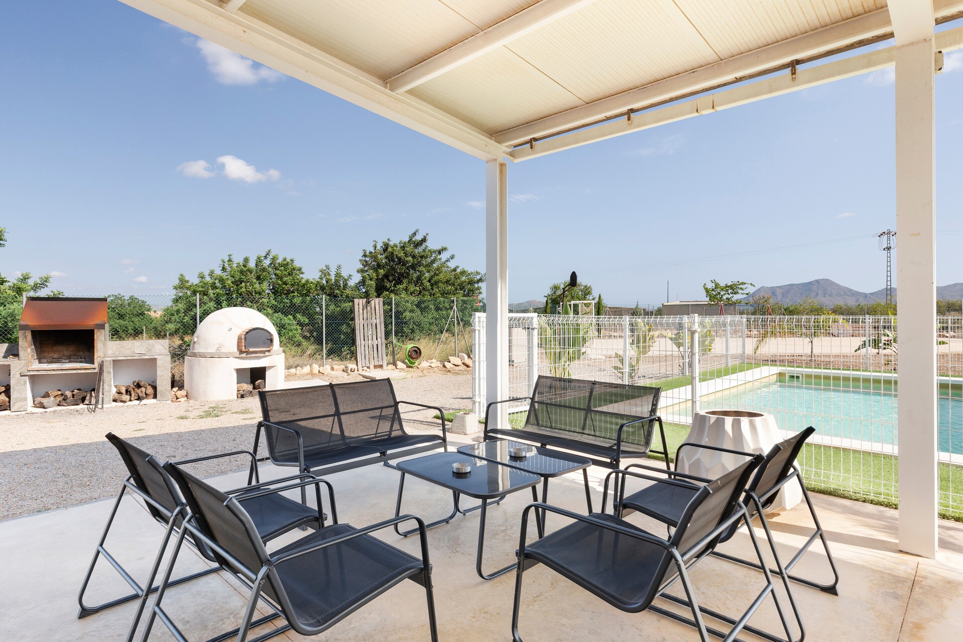 Un patio al aire libre con piscina, sillas de metal y una parrilla.