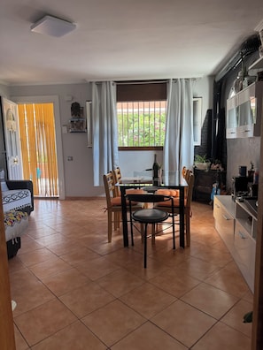 Zona pranzo con tavolo, sedie e vista sull'esterno attraverso una finestra.