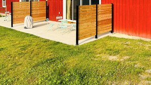 A red barn with a covered patio area, a wooden fence, and a grill. - Charming Cabin on horse farm minutes from Letchworth State park (Nunda)