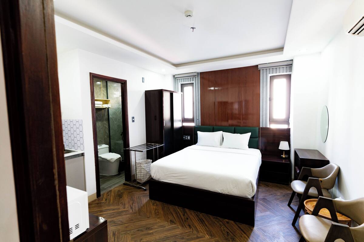 Une chambre d’hôtel avec un grand lit, un bureau, une chaise et une armoire.