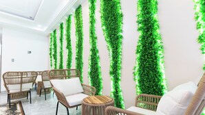 A lobby with wicker furniture, a marble floor, and vertical green plant walls. - MaMa Hotel And Apartment (Da Nang)