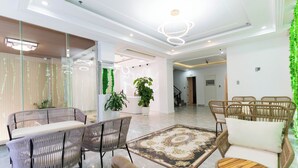 A modern hotel lobby with wicker furniture, a central rug, and green plants. - MaMa Hotel And Apartment (Da Nang)
