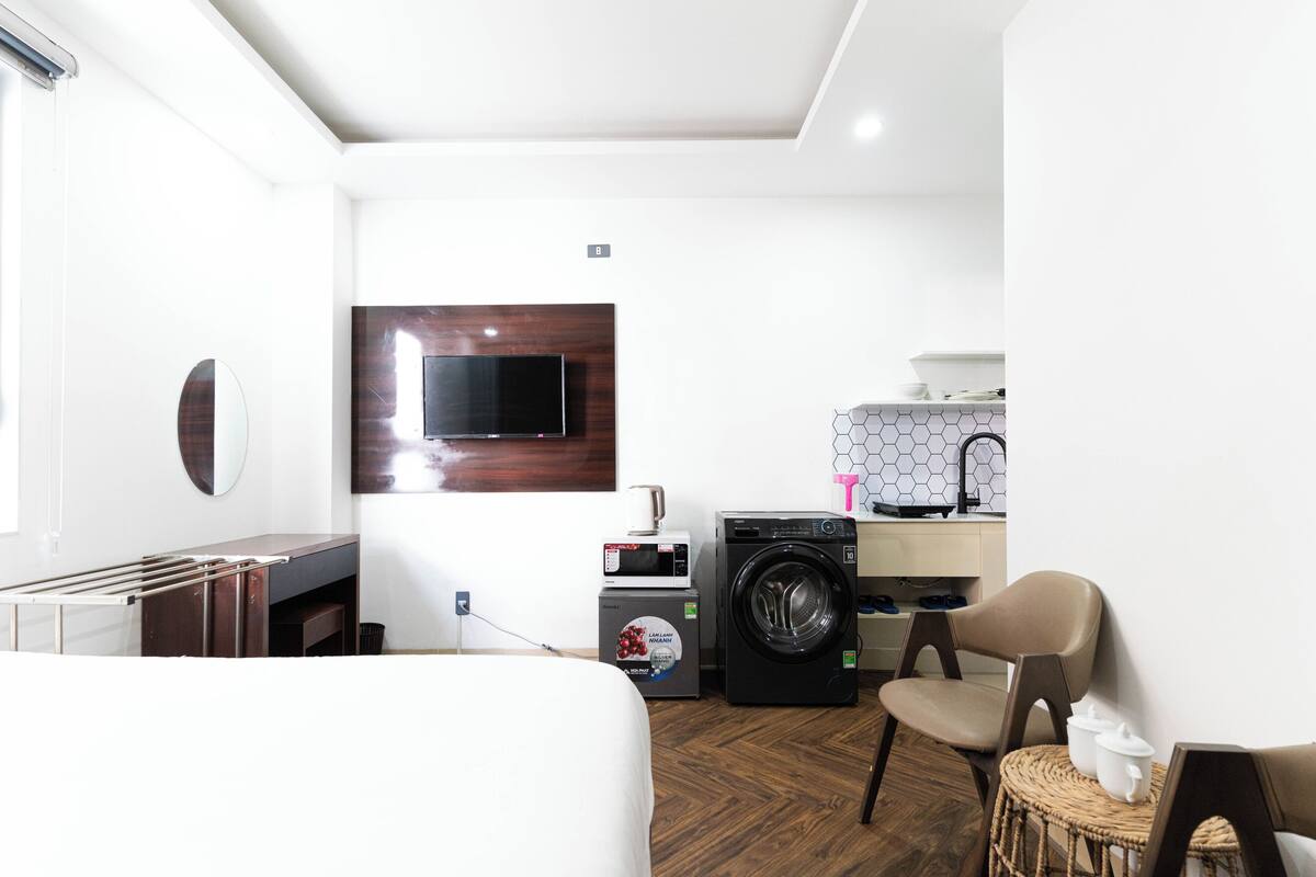 Une chambre d’hôtel compacte comprenant un lit, un lave-linge, un four à micro-ondes, une télévision et une petite kitchenette.