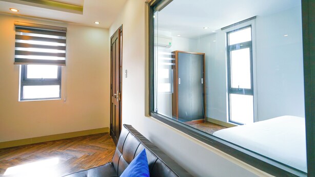 Una habitación de hotel con un ventanal grande, una cama, un banco y un armario.