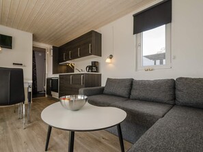 A modern living room with a grey sofa, a white coffee table, and a kitchen in the background. - 5 Person Holiday Park Home in Bryrup (Bryrup)