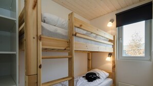 Une chambre avec un lit superposé, une fenêtre et une lampe fixée au mur.