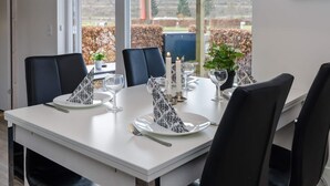 Une table à manger dressée avec des assiettes, des verres et des bougies, entourée de chaises.