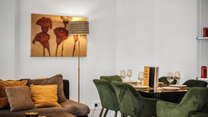 A modern living room with a sofa, a dining table set with glasses, and a lamp.
