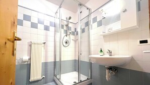 A bathroom with a glass-enclosed shower, a white sink, and a towel rack.