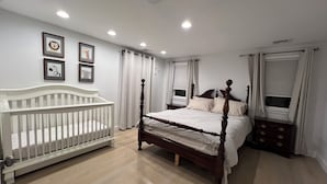 Una camera da letto con un letto di legno, una culla bianca e un comodino.