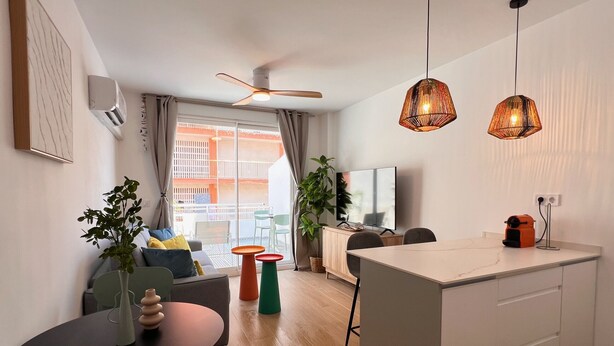 A modern apartment with a dining area, kitchen, and a balcony with a view.