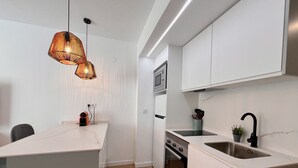 A modern kitchen with white cabinetry, a built-in oven, a sink, and a pendant light.