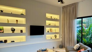 Un salon moderne comprenant un canapé, une table basse et des étagères intégrées ornées de divers objets décoratifs.