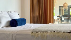 Un lit avec un oreiller à rayures blanches et bleues, un oreiller bleu et un plaid beige.