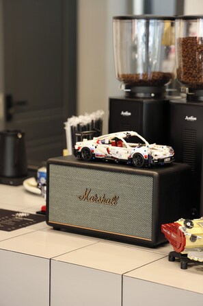 A coffee machine with a coffee bean hopper, a toy car on top, and a coffee maker on the side. - Palmira Hotel Bishkek (Bishkek)