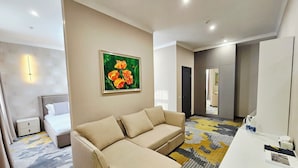 Una habitación de hotel con sofá, escritorio, un cuadro y una cama.