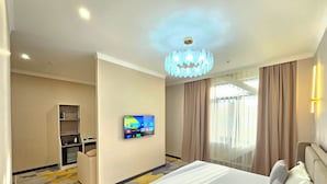 Habitación de hotel con cama, televisor montado en la pared, escritorio y armario.