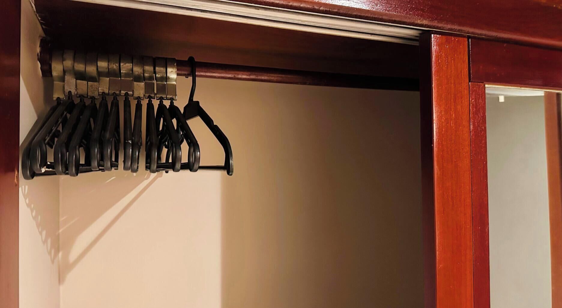 Ein Schrank mit Holztür und einem schwarzen Kleiderständer.