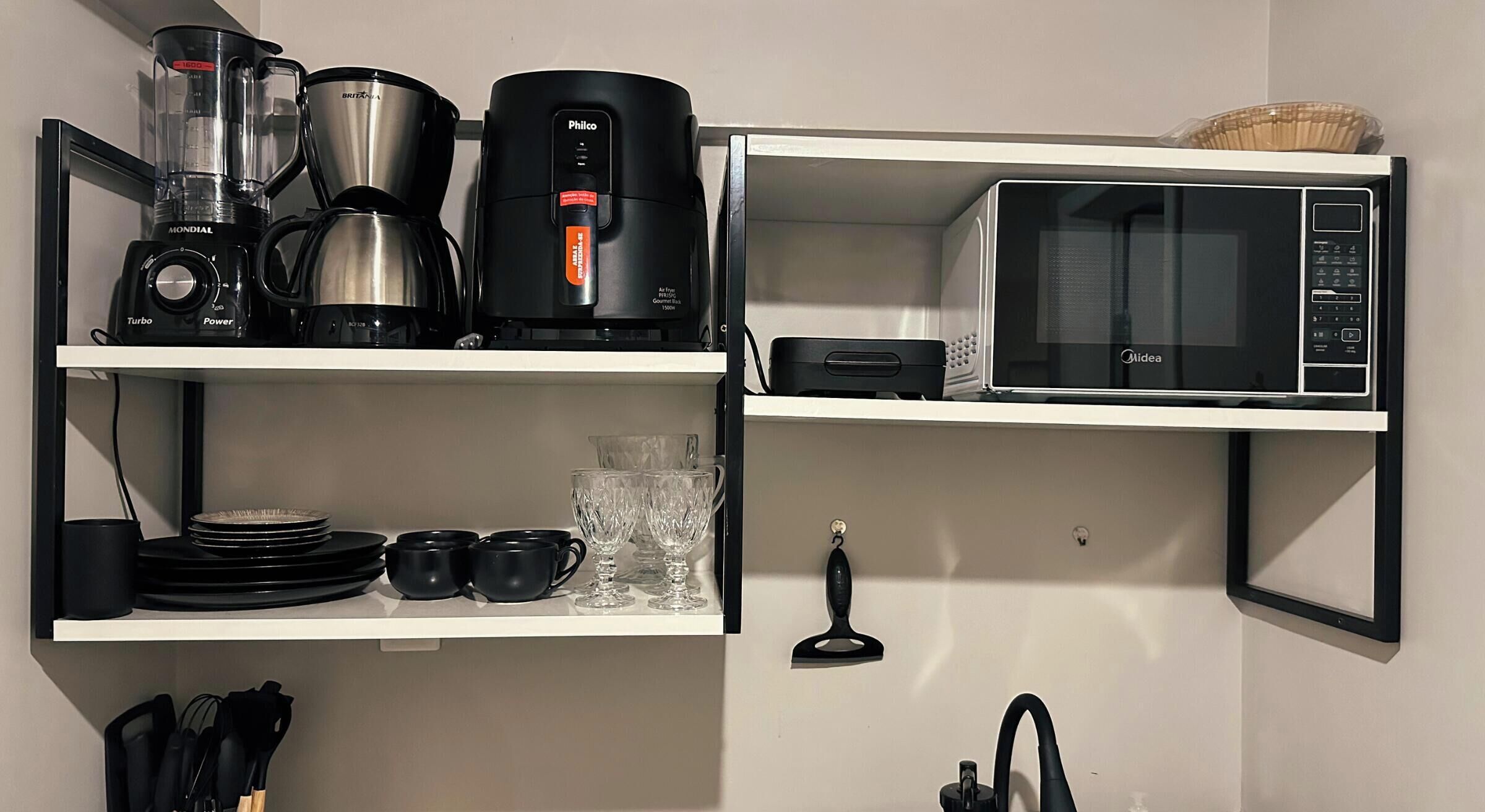 Una cocina con licuadora, cafetera y microondas en estantes.