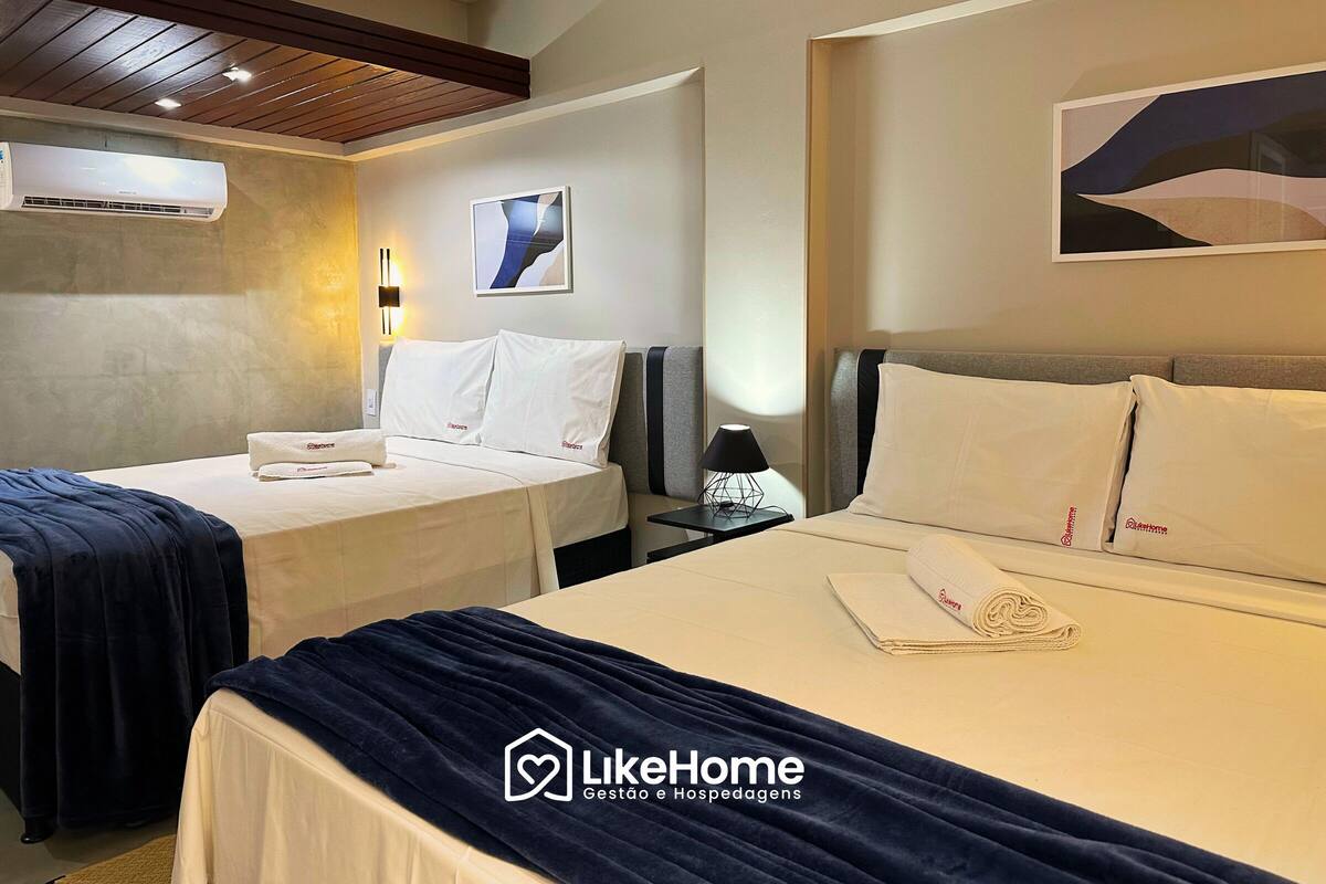Une chambre d’hôtel avec deux lits, une table de chevet, une lampe et un climatiseur fixé au mur.