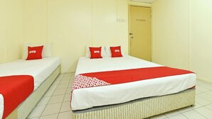 A hotel room with two single beds, each with a red OYO branded pillow. - Grand Heritage Hotel (Malacca City)