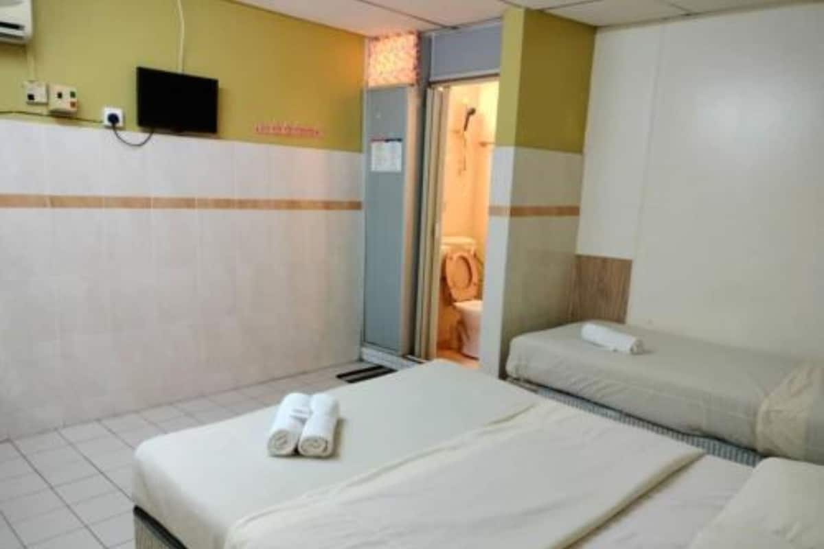 Ein Hotelzimmer mit zwei Betten, einem Fernseher und einem durch eine geöffnete Tür einsehbarer Badezimmer.