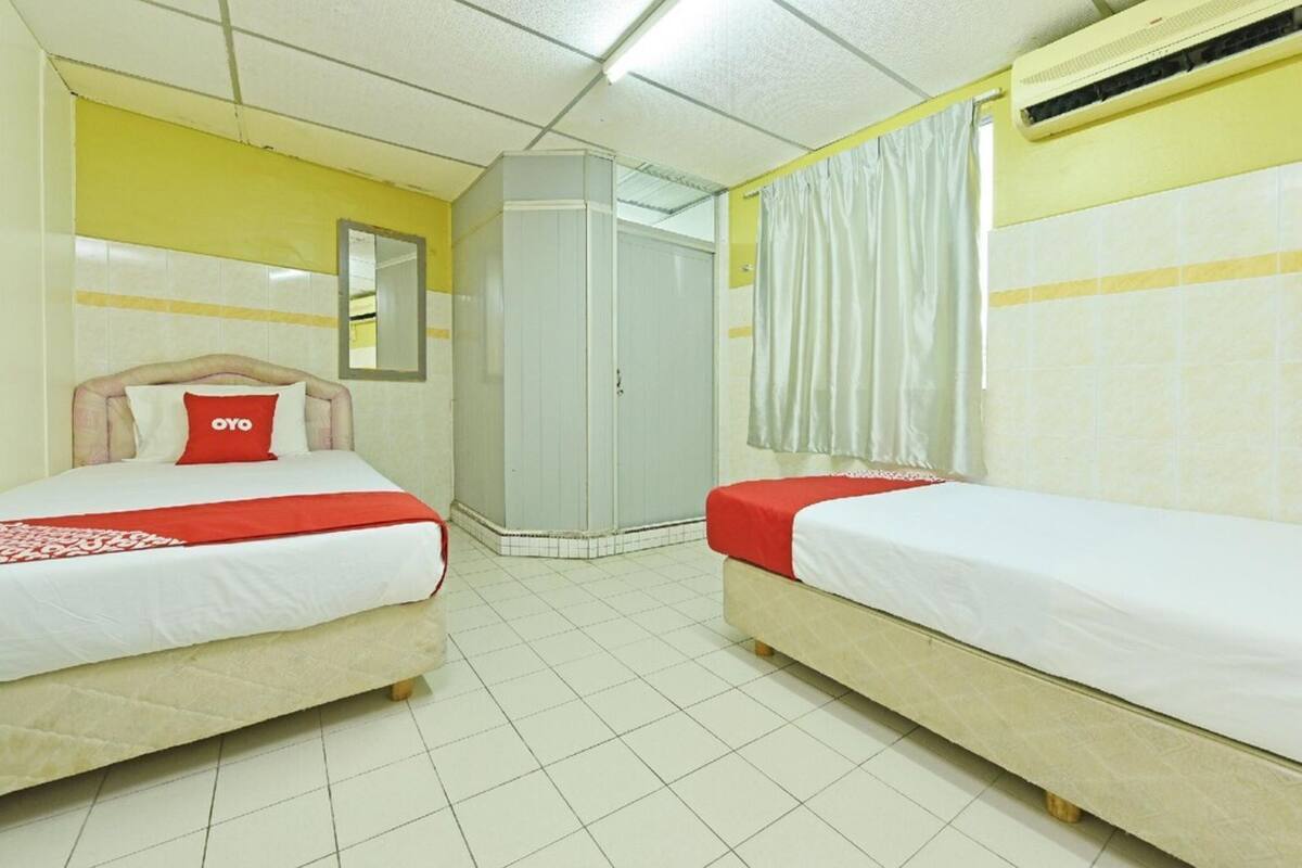 Ein Hotelzimmer mit zwei Betten, einem Spiegel, einem Kleiderschrank und einer Klimaanlage.