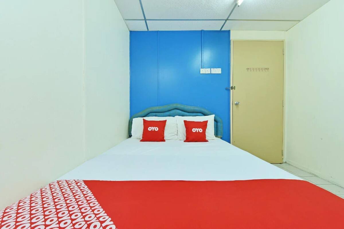 Ein Zimmer mit einem Bett, blauer Wand und einer Tür.