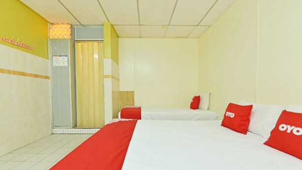 A hotel room with two beds, a red and white bedspread, and a red pillow with the logo "OYO". - Grand Heritage Hotel (Malacca City)