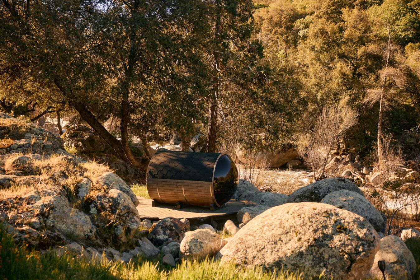A cylindrical structure in a natural setting with rocks and trees.