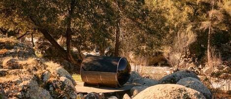 A cylindrical structure in a natural setting with rocks and trees.