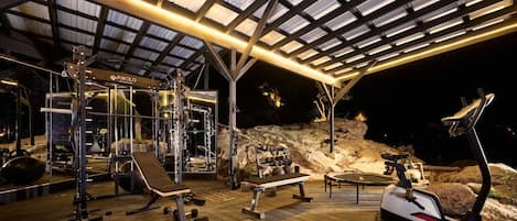 Ett gym med olika typer av träningsredskap, en bänk och en roddmaskin.