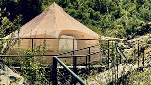Een grote, koepelvormige tent met een metalen hek er voor, omringd door groen.