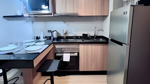 A modern kitchen with a built-in microwave, stainless steel refrigerator, and a dining area with a bench. - Fantástico estudio en CLC (Santiago)