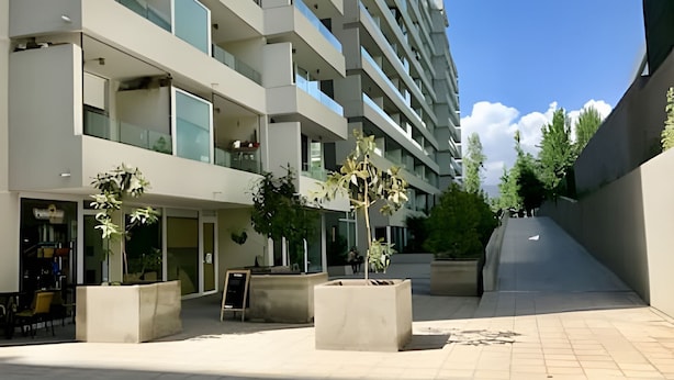 A modern building with multiple floors, outdoor seating, and potted. - Fantástico estudio en CLC (Santiago)