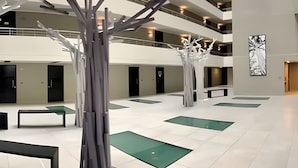 A spacious atrium with a modern design, featuring a central sculpture, multiple levels, and a minimalist aesthetic. - Fantástico estudio en CLC (Santiago)